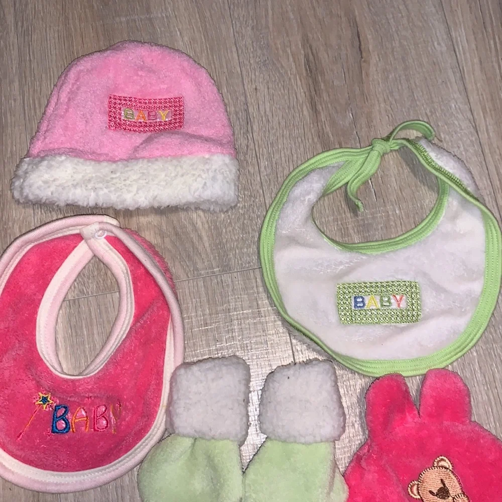 Colorful bundle of plush baby bibs, hats, and mittens